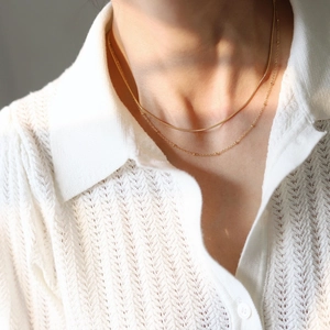 Detail of 18K gold-plated double-layer snake and bead chain necklace on a model