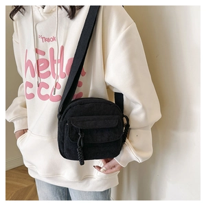 Detail of black corduroy shoulder bag with textured stripes and front flap pocket