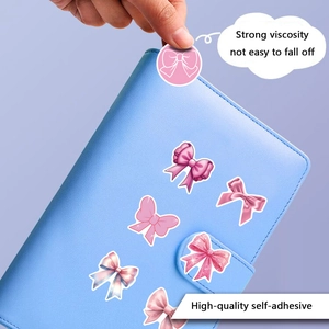 Detail of pink coquette bow sticker being applied to a notebook showing strong adhesion