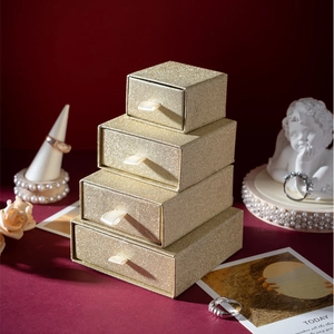 Glittering gold drawer jewelry boxes with beige ribbon pulls in four stackable sizes