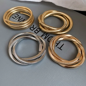 Detailed macro view of spiral metallic bangles in gold and silver with threaded texture