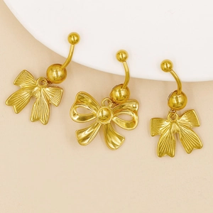 Detailed close-up of three golden bow-shaped belly rings with sparkling crystals