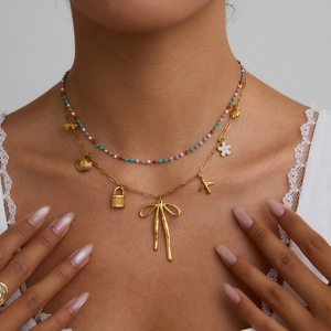 Layered gold necklace with colorful beads and butterfly lock pendant on model