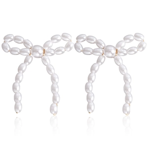 Elegant bow earrings featuring white pearls and gold metal finish on white background