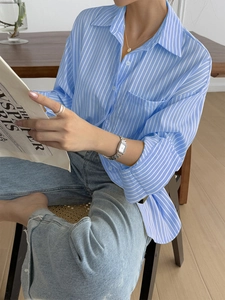 Close-up of a blue striped long-sleeved shirt styled with jeans in a relaxed setting