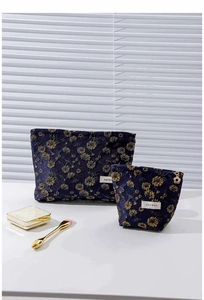 Detail of navy and purple floral embroidery on canvas cosmetic bags with gold daisy zippers