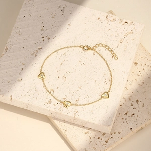Detail of gold S925 silver heart bracelet with small zircon on marble stone background