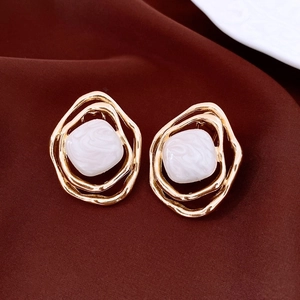 Close-up of golden irregular rhombic earrings with cream-colored square resin stone inlay