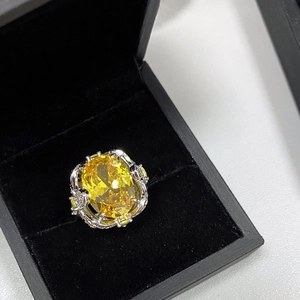 Detailed close-up of a large yellow oval gemstone ring inside a premium black jewelry box