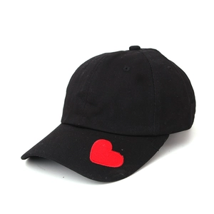 Close-up of black cotton baseball cap with a red heart embroidery on the brim side
