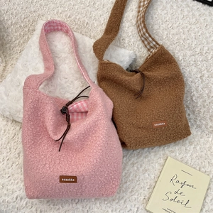 Detalle de bolsos bandolera de forro polar con logo de cuero y forro de cuadros