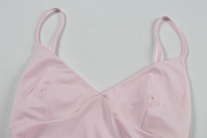 Detail of a pale pink satin camisole featuring a deep V-neck and thin spaghetti straps