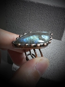 Detailed close-up of natural labradorite gemstone ring with vintage bronze wire-wrapped band