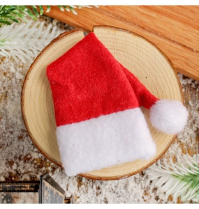 Close-up of mini red Christmas hat with white pompom on rustic wooden background