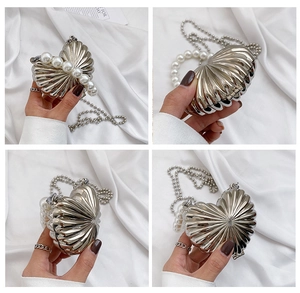 Detail of silver heart-shaped mini shell evening bag with pearl and metal chain straps
