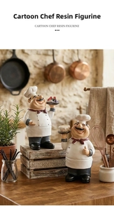 Detail of two resin chef figurines holding fruit and cake for rustic kitchen decor