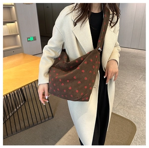 Detail of dark brown corduroy shoulder bag featuring embroidered red strawberry patterns