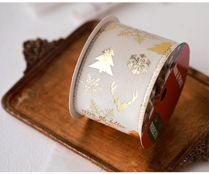 Detail of cream Christmas ribbon with gold reindeer and tree prints on vintage tray