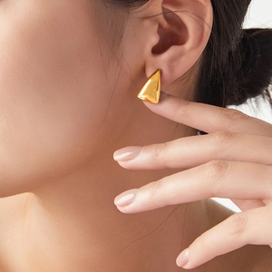 Minimalist gold triangle stud earrings made of titanium steel worn by a female model