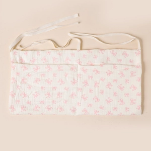 Détail du sac de rangement en coton blanc avec nœuds roses et double poche pour bébé