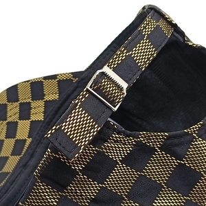 Macro detail of plaid baseball cap back with gold grid pattern and silver metal buckle