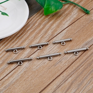 Detailed view of six silver stainless steel cylindrical clasps on a rustic wood background