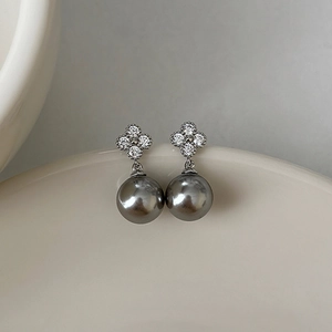 Détail de boucles d'oreilles argentées avec fleurs en zircon et perles gris foncé