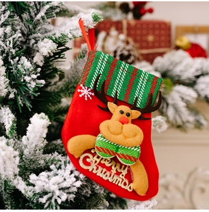 Close-up of a plush reindeer Christmas stocking hanging on a snowy festive tree branch