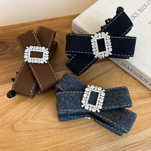 Detailed close-up of bow hair clips in velvet fabric with crystal buckles on a wooden table