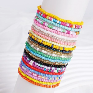 Detail of multi-layered colorful seed bead bracelet set on a white cylinder stand