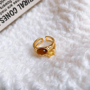 Macro detail of gold plated tiger eye ring with cubic zirconia on white fur backdrop