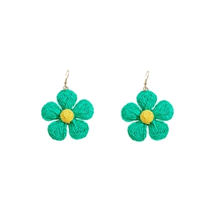 Macro detail of handmade woven raffia flower earrings in vibrant yellow and green