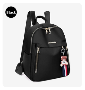 Detail of black oxford backpack featuring gold zippers and a cute teddy bear charm