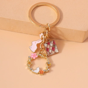 Pink rabbit and floral wreath keychain accessory with enamel and rhinestones in gold finish