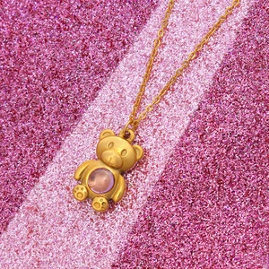 Golden titanium bear pendant necklace with a pink stone on a glitter background