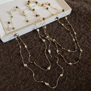 Detail of 18k gold plated long necklaces with tiger eye beads and baroque pearls