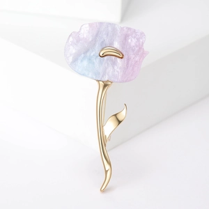 Macro shot of purple gradient flower brooch with golden stem on a white background