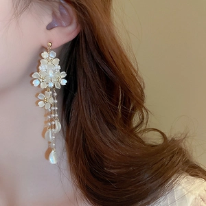 Detailed view of floral pearl tassel earrings with gold plating on female model