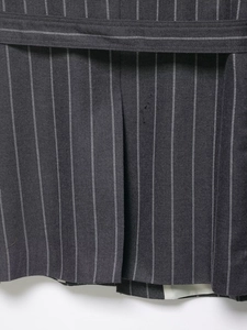 Detail of dark gray striped suit jacket back featuring a refined vent and matching belt