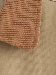 Detailed close-up of caramel corduroy and khaki canvas patchwork fabric on jacket