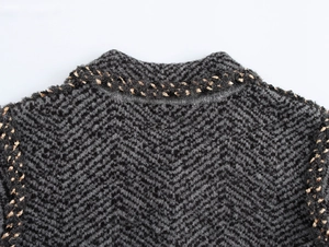 Macro detail of V-shaped herringbone knit texture and woven trim on neck and shoulder