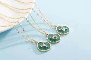 Macro view of gold zodiac necklaces with green malachite pendants and rhinestone symbols