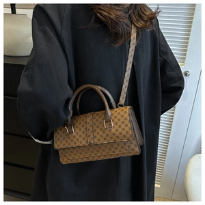 Detail view of brown satchel bag with black circular patterns and gold-tone metal hardware