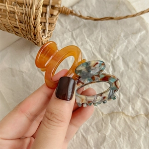 Chic resin oval hair claw clips in amber and marble patterns for elegant hair styling