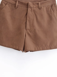 Detail of brown woven shorts showing belt loops, pockets and fine stitching craftsmanship