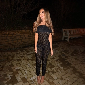 Detail of black lace off-shoulder slim jumpsuit with see-through floral pattern