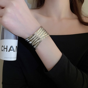 Macro detail of silver wide cuff bracelet featuring unique liquid metal ripple textures