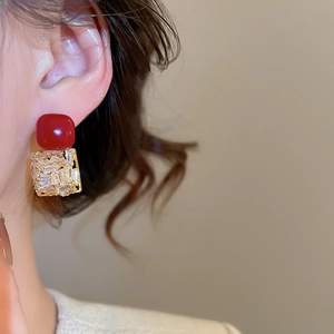 Détail de boucles d'oreilles carrées en zircon rouge avec monture dorée sur un mannequin