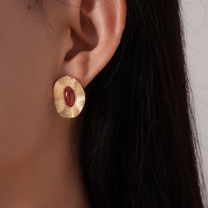 Gros plan de boucles d'oreilles vintage dorées avec gemme rouge ovale sur un mannequin