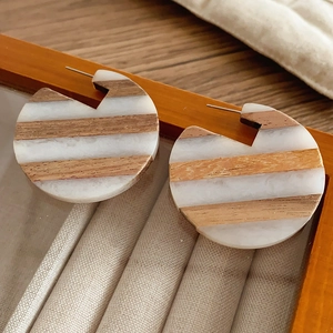 Detail of C-shaped earrings with geometric wood texture and white marble resin stripes